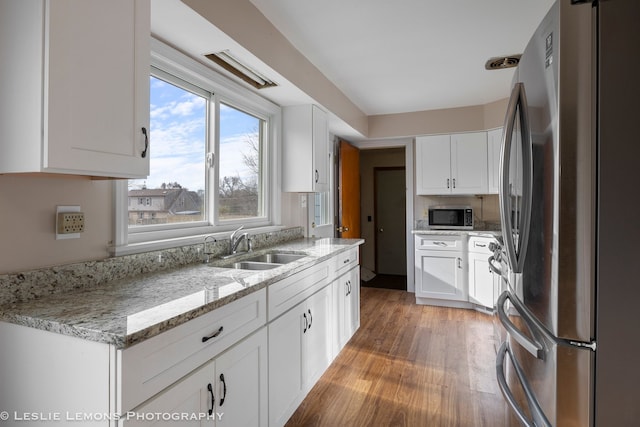 kitchen featuring white cabinetry, sink, wood-type flooring, and appliances with stainless steel finishes