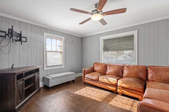 living room featuring dark parquet flooring, wooden walls, ceiling fan, and crown molding