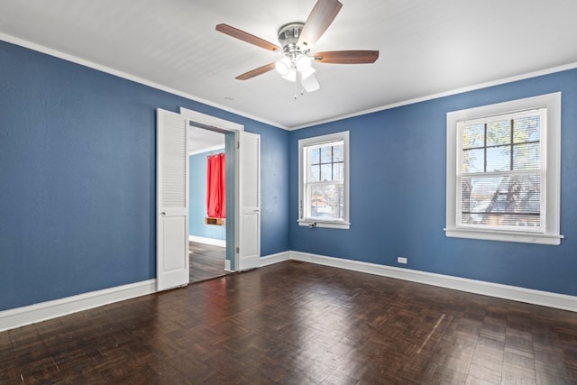 empty room featuring parquet floors, crown molding, ceiling fan, and a healthy amount of sunlight