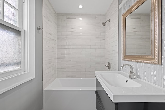 bathroom featuring plenty of natural light, tiled shower / bath, and vanity