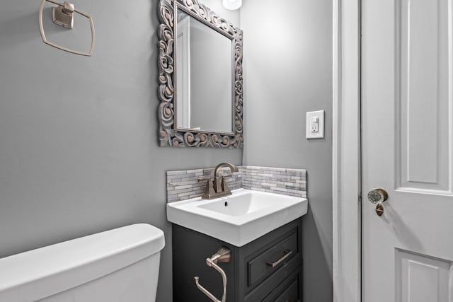 bathroom with decorative backsplash, toilet, and vanity