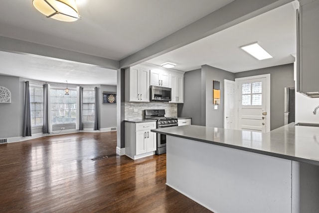 kitchen with white cabinets, stainless steel appliances, a wealth of natural light, and dark wood-type flooring