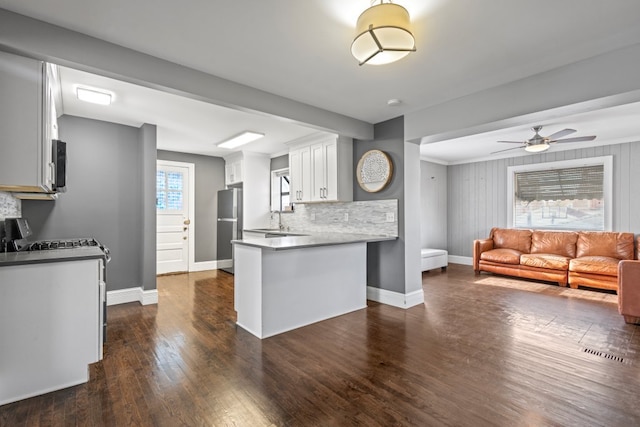 kitchen featuring kitchen peninsula, decorative backsplash, dark hardwood / wood-style floors, white cabinetry, and stainless steel appliances