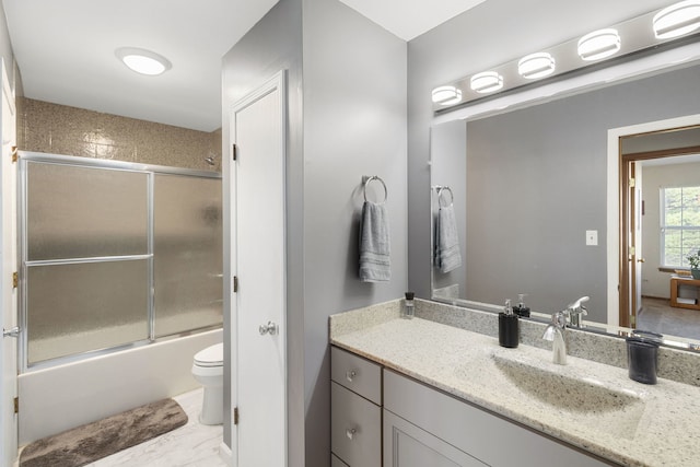 full bathroom featuring vanity, bath / shower combo with glass door, and toilet