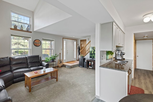 living room featuring light wood-type flooring, sink, and vaulted ceiling