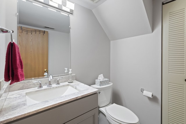 bathroom with toilet, vanity, and vaulted ceiling