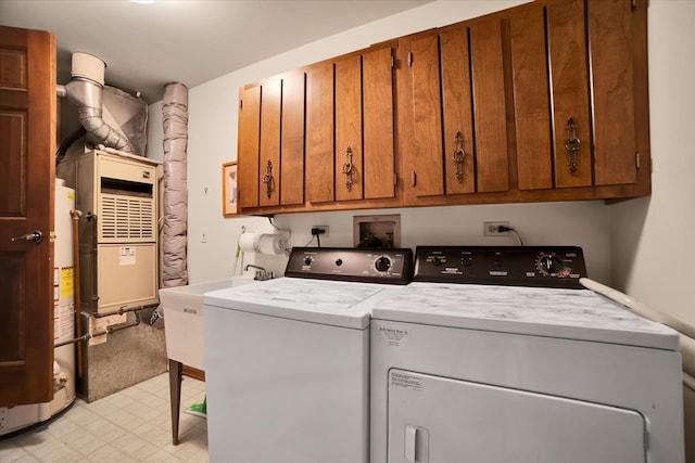 washroom with cabinets, washing machine and dryer, and gas water heater