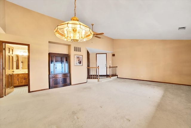 carpeted spare room with ceiling fan with notable chandelier and lofted ceiling