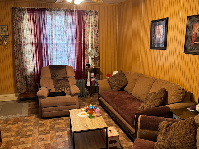 living room with radiator heating unit, ceiling fan, and wood walls