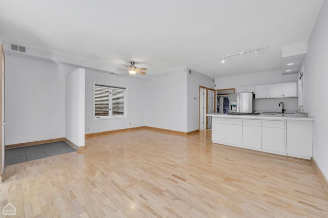 unfurnished living room with sink, ceiling fan, and light hardwood / wood-style flooring