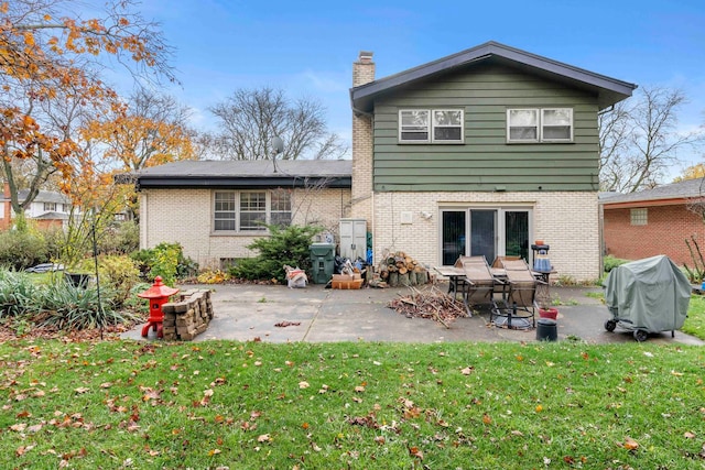 back of property featuring a yard, a fire pit, and a patio area