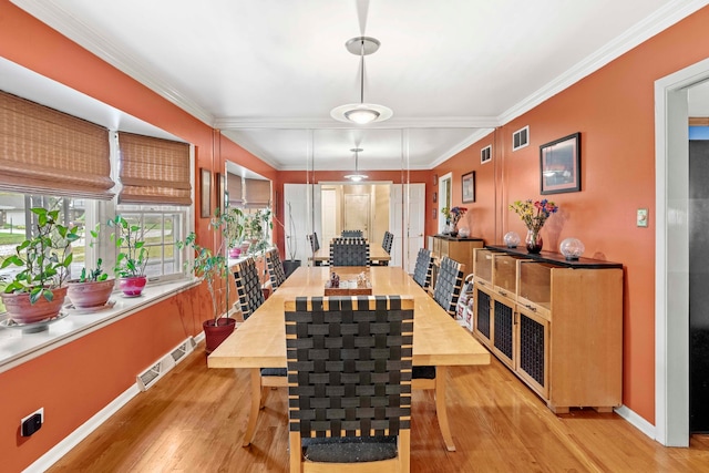 dining area with crown molding and light hardwood / wood-style floors