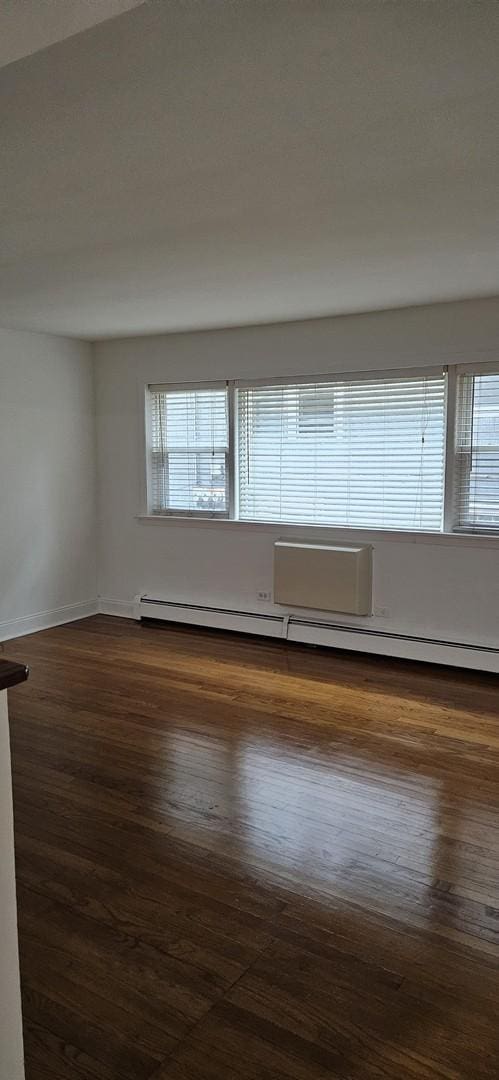 spare room with baseboard heating, dark wood-type flooring, and a wealth of natural light