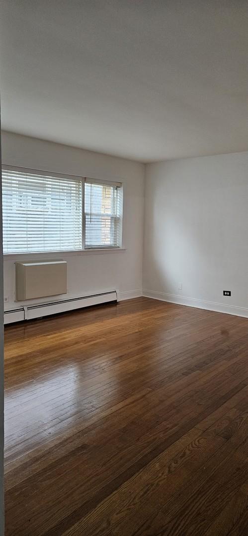 empty room featuring dark hardwood / wood-style floors and baseboard heating