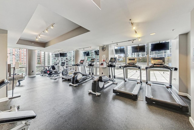 exercise room featuring track lighting and a tray ceiling