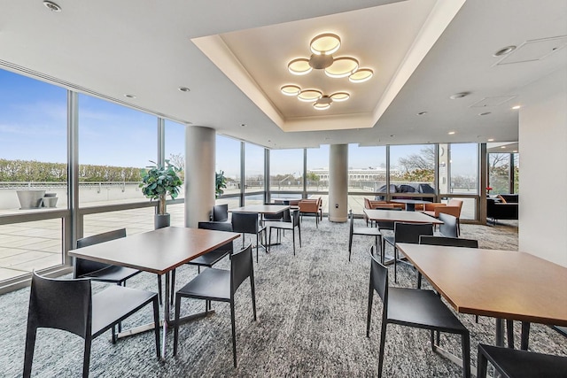 dining space featuring a raised ceiling and a wall of windows