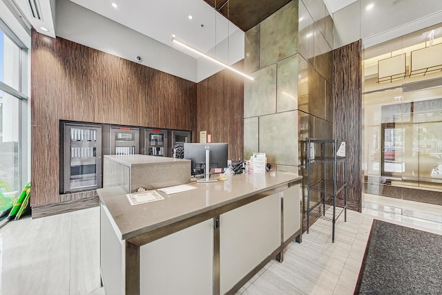 kitchen with white cabinetry, plenty of natural light, light tile patterned flooring, and a high ceiling