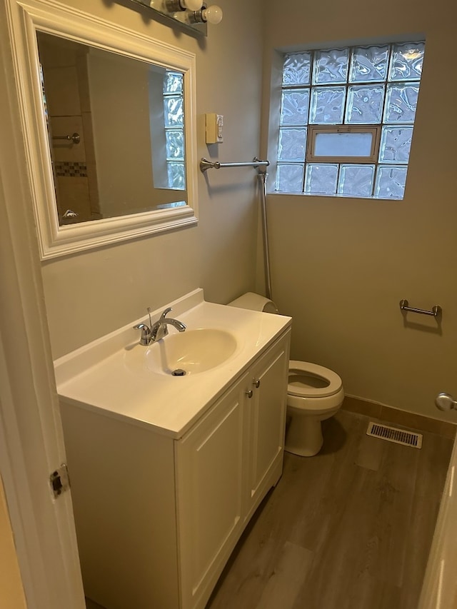 bathroom with toilet, vanity, a wealth of natural light, and hardwood / wood-style floors