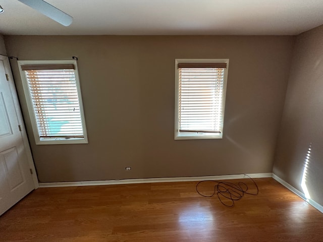 spare room featuring a wealth of natural light, wood-type flooring, and ceiling fan