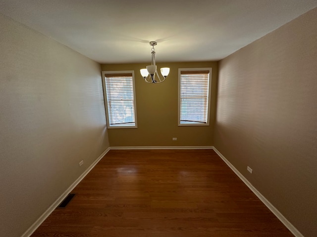 unfurnished dining area with dark hardwood / wood-style flooring and a chandelier