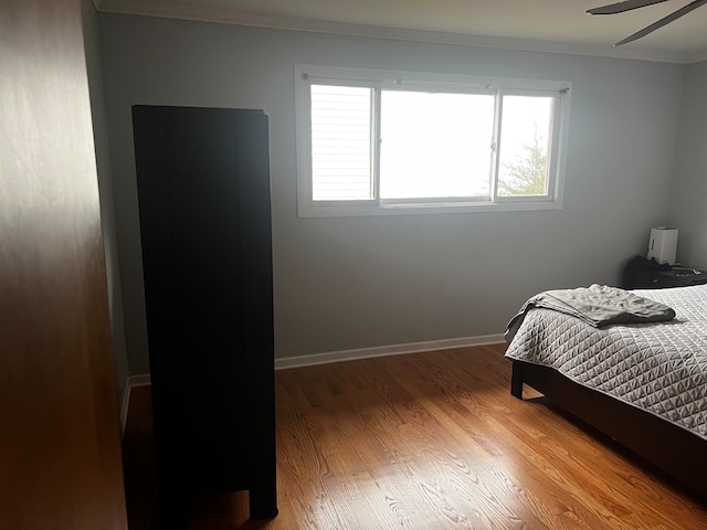 bedroom with hardwood / wood-style floors, ceiling fan, and crown molding