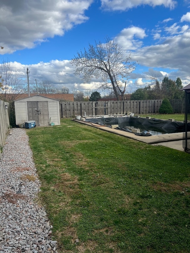 view of yard featuring a covered pool and a storage unit