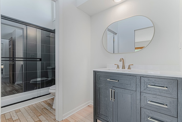 bathroom with toilet, vanity, hardwood / wood-style flooring, and a shower with door