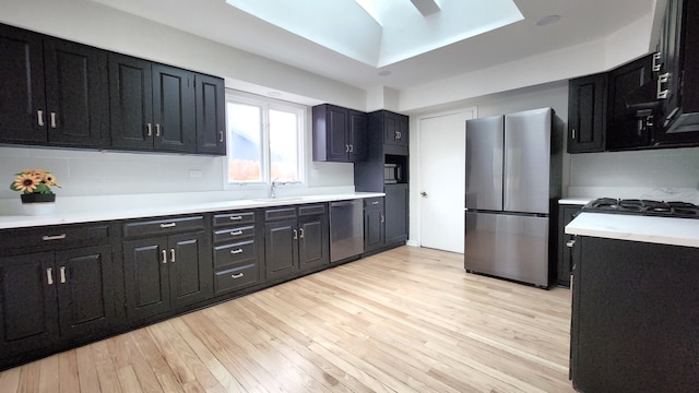 kitchen with sink, light wood-type flooring, decorative backsplash, and stainless steel appliances