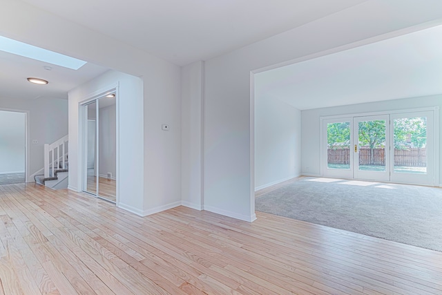 unfurnished room featuring light hardwood / wood-style flooring and a skylight