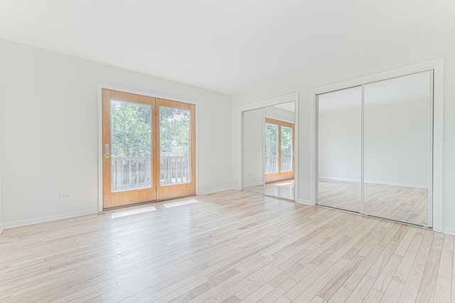 unfurnished bedroom with light hardwood / wood-style floors and two closets