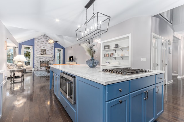 kitchen with a fireplace, appliances with stainless steel finishes, vaulted ceiling, and blue cabinets