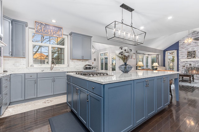 kitchen with a fireplace, dark wood-type flooring, decorative light fixtures, and stainless steel gas cooktop