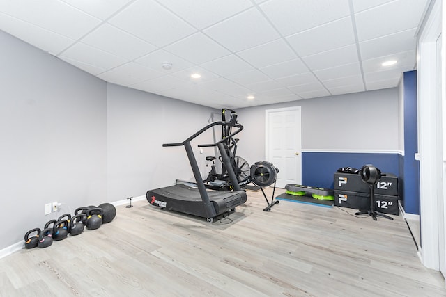 workout room with a paneled ceiling and light hardwood / wood-style floors