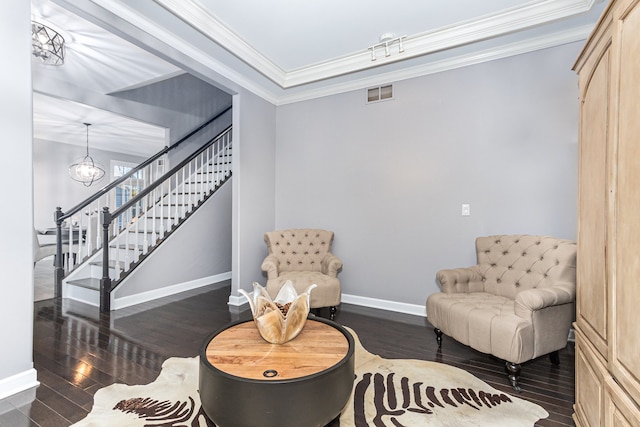 living area featuring an inviting chandelier, crown molding, and dark wood-type flooring