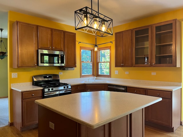 kitchen featuring light wood-type flooring, pendant lighting, a kitchen island, and appliances with stainless steel finishes