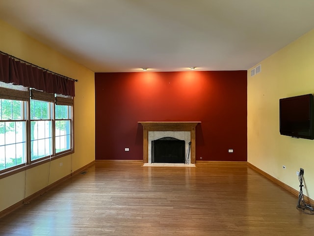 unfurnished living room featuring light wood-type flooring and a tile fireplace