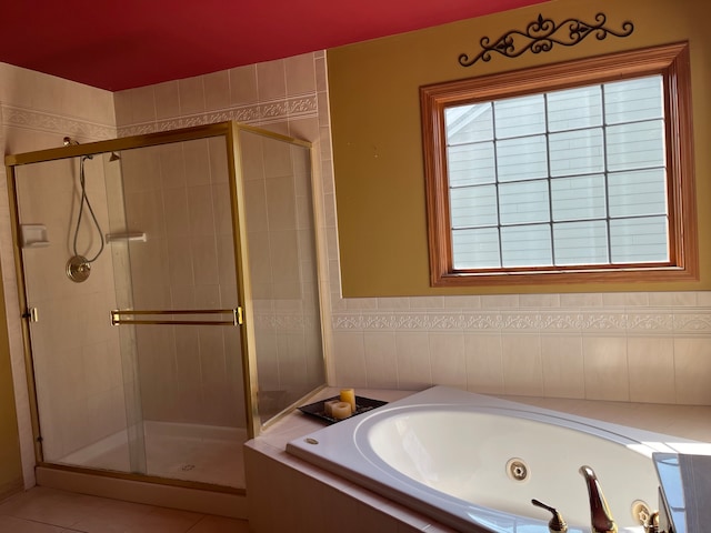 bathroom with independent shower and bath, tile patterned flooring, and tile walls