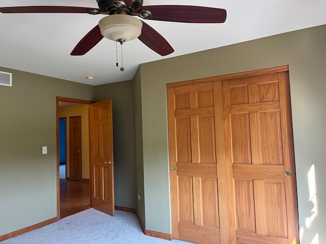 unfurnished bedroom featuring a closet, light colored carpet, and ceiling fan