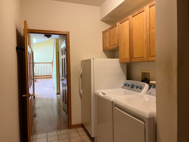 washroom with light wood-type flooring, cabinets, and washing machine and clothes dryer