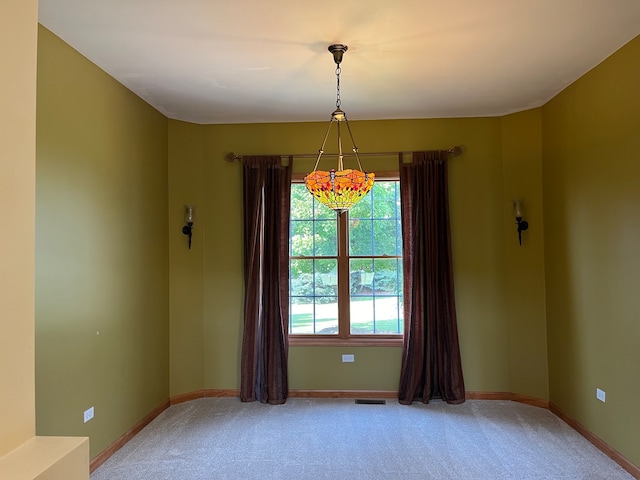 unfurnished room with a notable chandelier and carpet floors