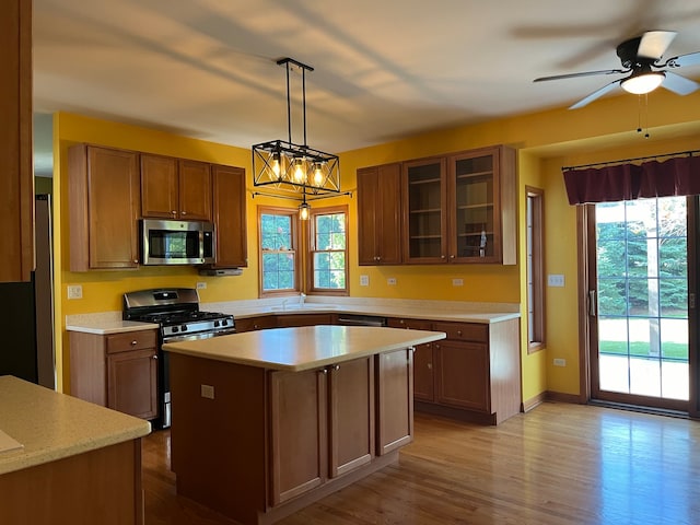 kitchen featuring a wealth of natural light, stainless steel appliances, hanging light fixtures, and a kitchen island