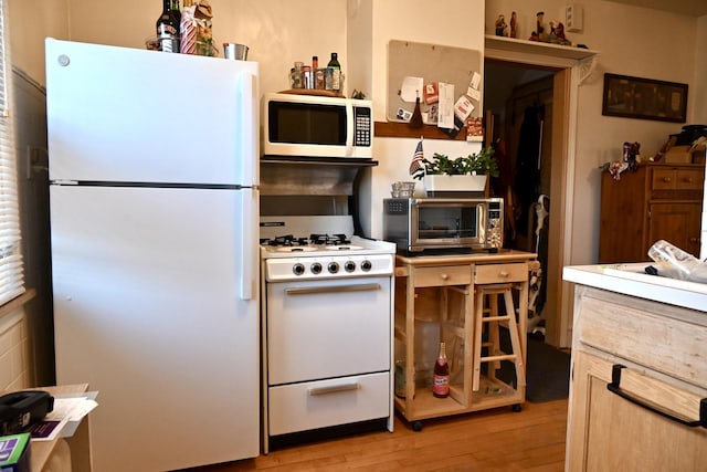 kitchen with white appliances and light hardwood / wood-style floors