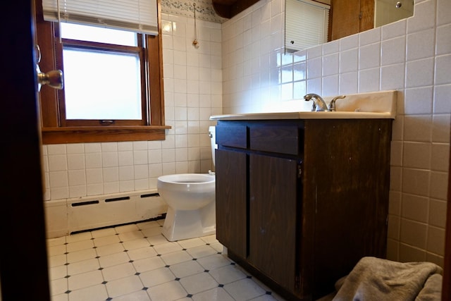 bathroom with a baseboard radiator, tile walls, vanity, and toilet