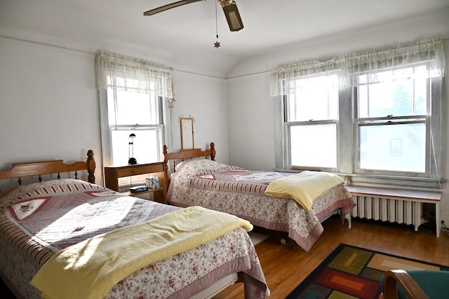 bedroom with wood-type flooring, lofted ceiling, radiator heating unit, and ceiling fan