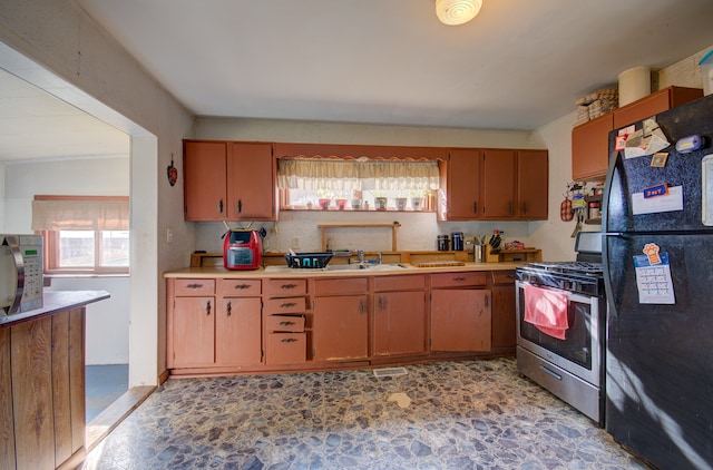 kitchen with black fridge, sink, and stainless steel gas range