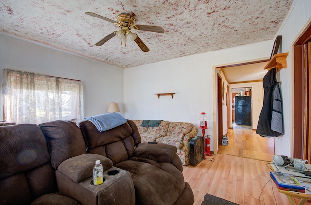 living room with hardwood / wood-style floors, ceiling fan, wood walls, and ornamental molding