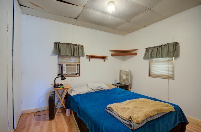 bedroom featuring a drop ceiling, wood-type flooring, and cooling unit