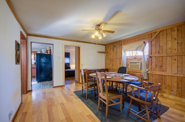 dining area with ornamental molding, light hardwood / wood-style floors, and wooden walls