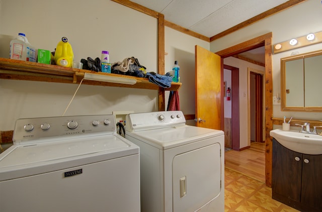 washroom featuring light parquet floors, a textured ceiling, sink, washing machine and clothes dryer, and crown molding