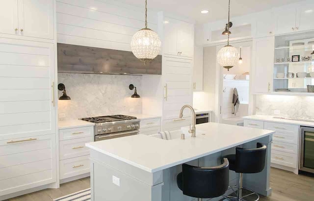 kitchen with white cabinetry, decorative backsplash, sink, and a center island with sink